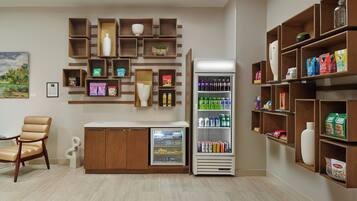Una habitación con zona de estar, refrigerador y estantes con diversos objetos.