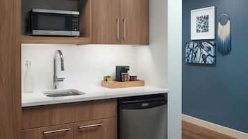 Cocina moderna con armarios de madera, microondas, cafetera y lavavajillas.