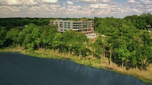 A hotel with multiple floors, surrounded by dense greenery and a body of water. - Element by Marriott Bainbridge Riverfront (Bainbridge)
