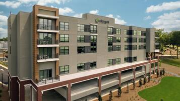 A multi-story hotel with a flat roof, large windows, and a covered outdoor area with a parking lot.