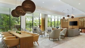 A spacious living area with a wooden dining table, multiple chairs, a sofa, and a TV mounted on the wall. - Element by Marriott Bainbridge Riverfront (Bainbridge)