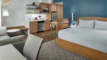 A hotel room with a bed, a desk, a kitchenette, and a seating area.