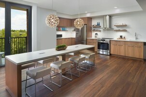 A modern kitchen with a central island, bar stools, stainless steel appliances, and a view to the outdoors.