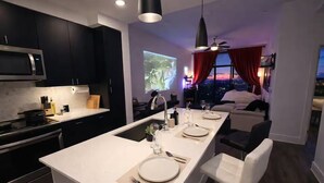 A modern kitchen with a central island, a dining area with a view, and a cozy seating area with a large window. - Home Movie Theatre. Walk to FIFA/NRG/Med Center. 1BDR Highrise (Houston)