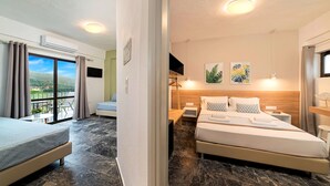 Habitación de hotel con cama, sofá, televisión y balcón con cortinas.