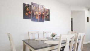 Un espace repas comprenant une table rectangulaire, six chaises et trois tableaux accrochés au mur.