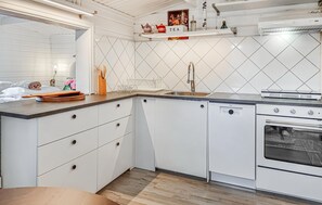 A kitchen with white cabinetry, a dishwasher, an oven, a sink, and a countertop with various kitchen items. - Cozy home in Göta with WiFi (Göta)