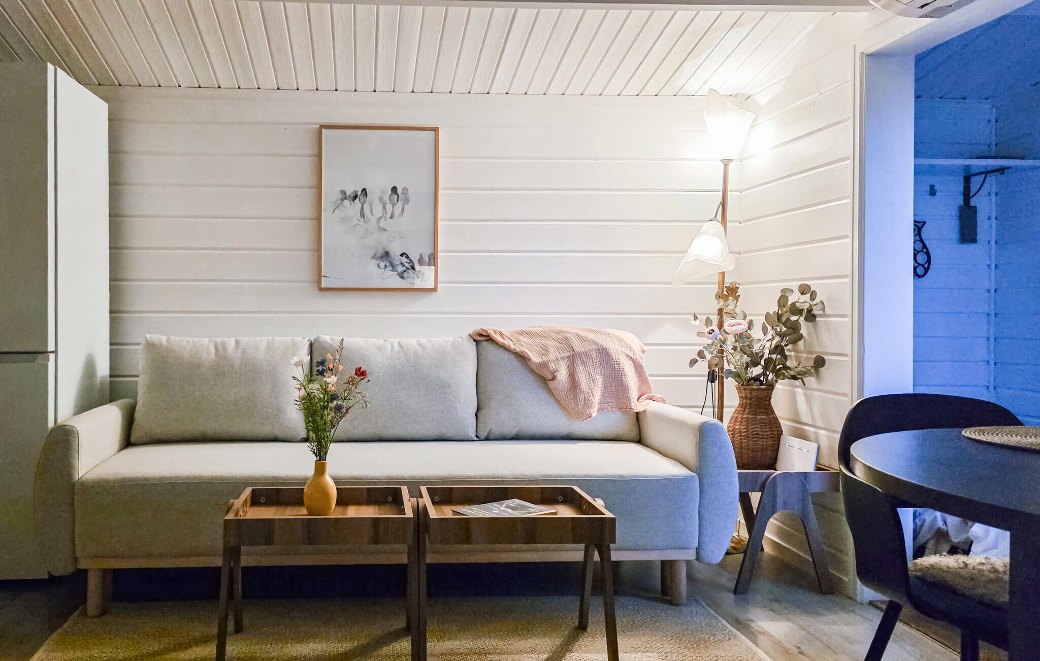 A living room with a sofa, a coffee table, a lamp, and a framed picture on the wall.