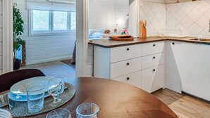 Ett modernt kök med vita skåp, en bänkskiva i trä och en matplats med ett bord för fyra personer.