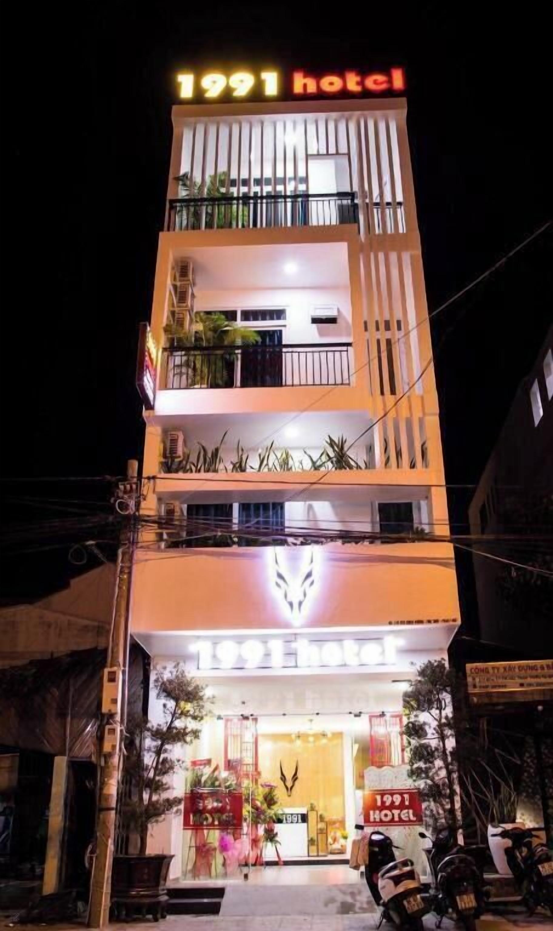 Un immeuble à plusieurs étages, avec une enseigne indiquant « Hôtel 1991 » à l’entrée.