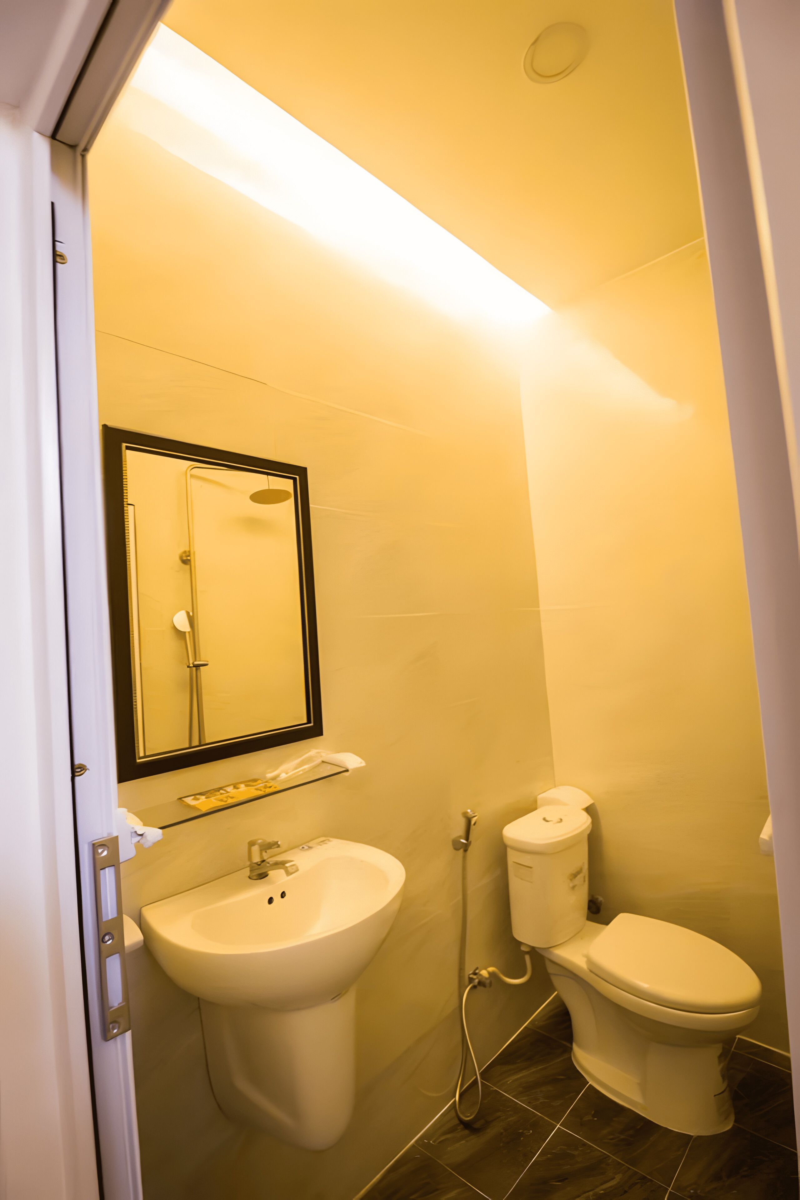 Un baño con lavamanos, inodoro y espejo sobre el lavamanos.