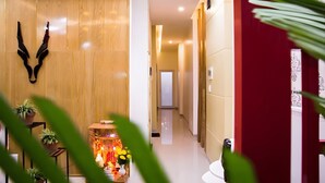 Un pasillo con pared de madera, una puerta roja y una pequeña mesa con plantas y adornos.
