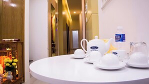 Una mesa redonda con un juego de té, una botella de agua y una jarrón.