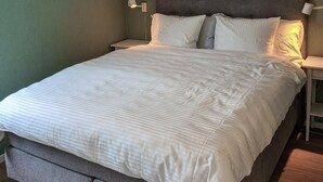 Una cama bien hecha con un edredón a rayas, dos almohadas y un cabecero.