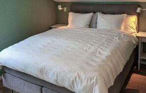 Una cama bien hecha con un edredón a rayas, dos almohadas y un cabecero.