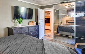 Une chambre à coucher comprenant un lit, une commode, un miroir et un placard avec une porte coulissante.