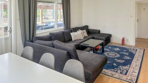 Un salon comprenant un canapé, une table basse, une table à manger, un tapis à motifs et une vue par la fenêtre.