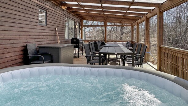 Une terrasse en bois avec un jacuzzi, des sièges d’extérieur et un barbecue.