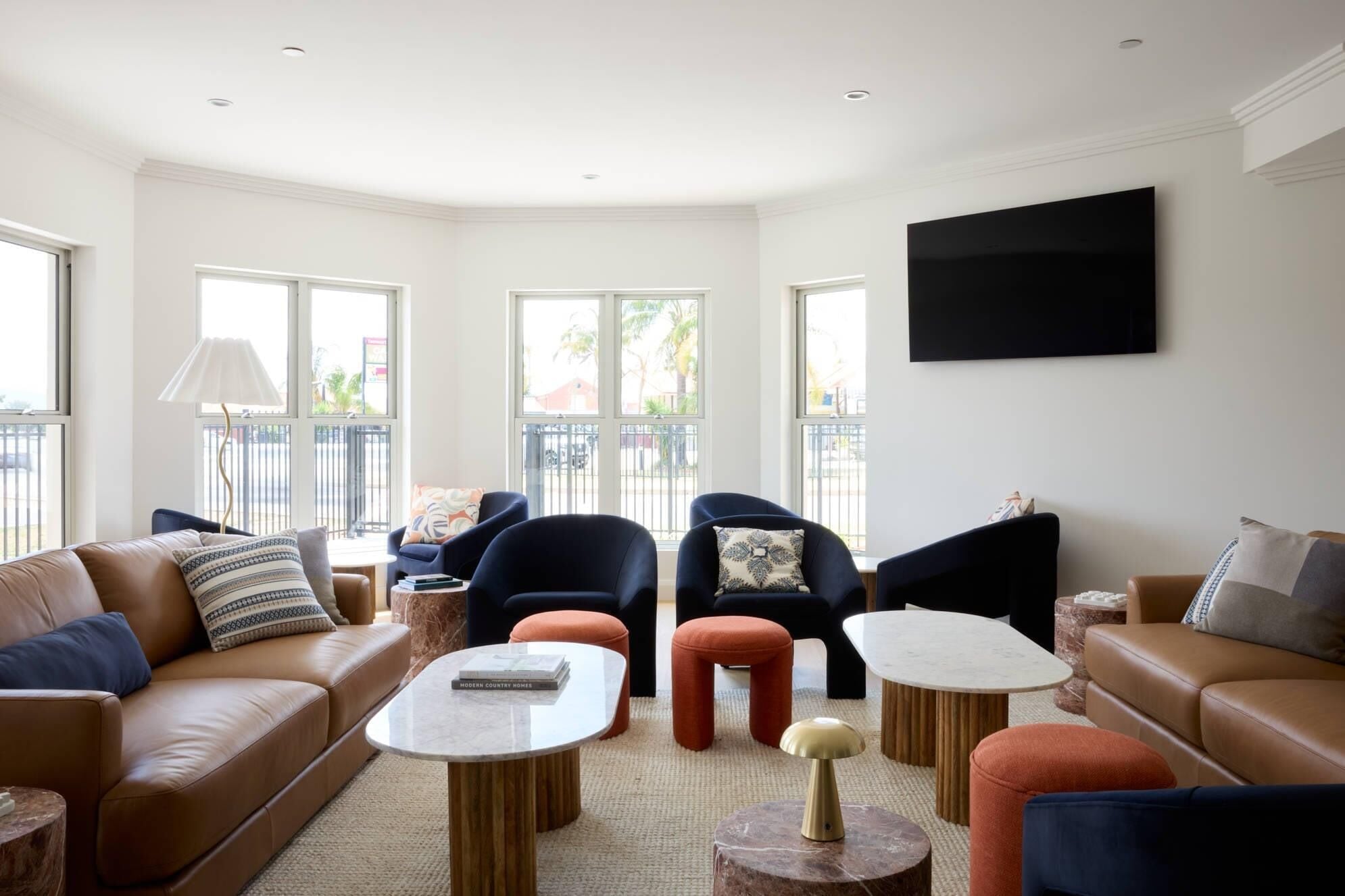 A modern living room with leather sofas, a flat-screen TV, and a large window with a view.