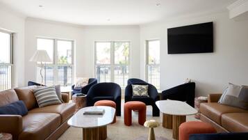 A modern living room with leather sofas, a flat-screen TV, and a large window with a view.