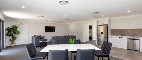 A modern kitchen with white cabinets, stainless steel appliances, and a dining area with a marble table and black chairs.