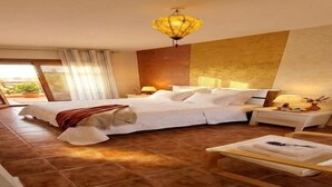Une chambre à coucher avec un grand lit, une table de chevet, une commode, une chaise et un luminaire au plafond.