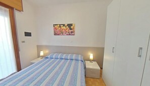 Une chambre à coucher avec un lit, deux tables de chevet avec des lampes, une armoire et un tableau au mur.