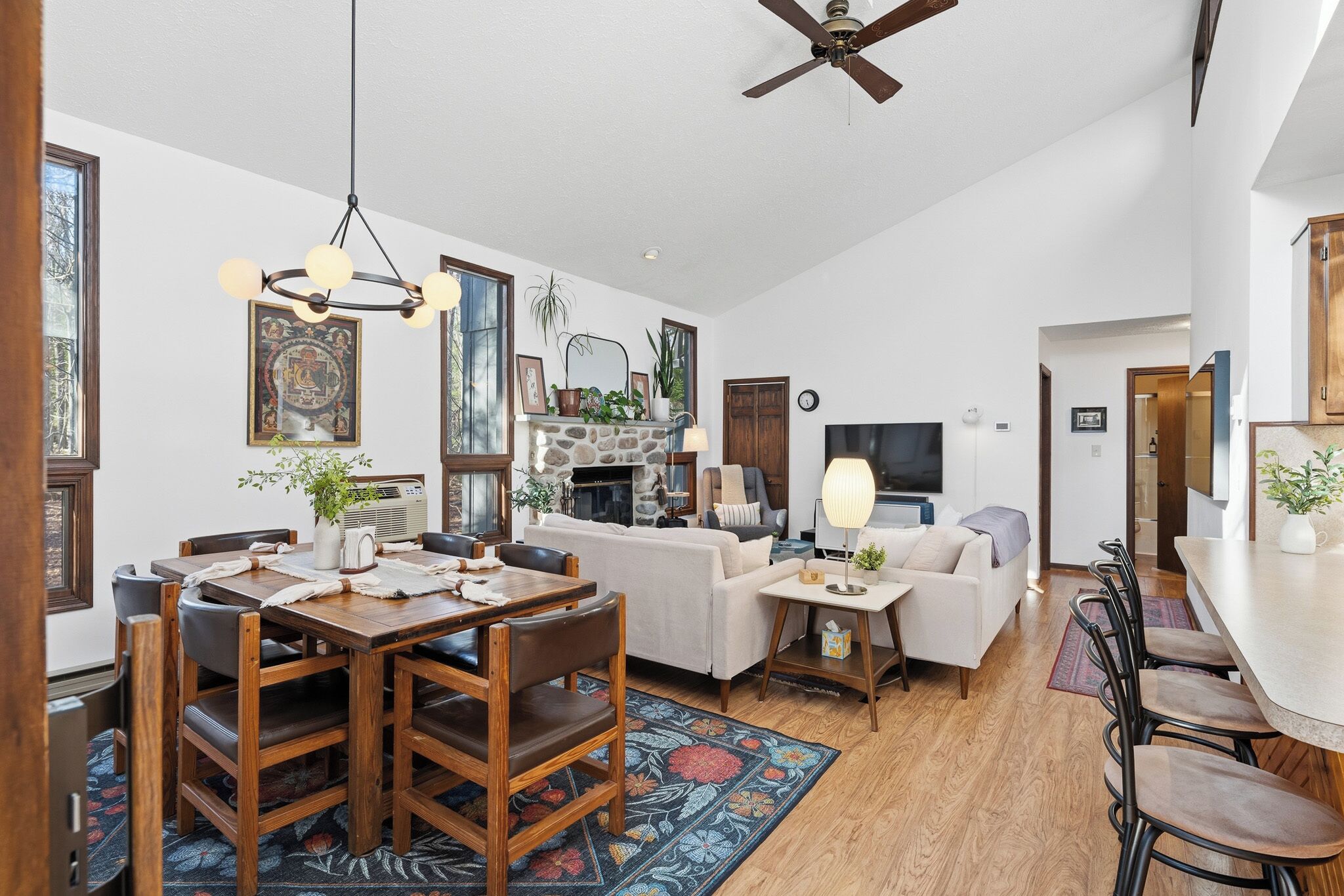 A spacious living area with a fireplace, a dining table with chairs, a sofa, and a television.