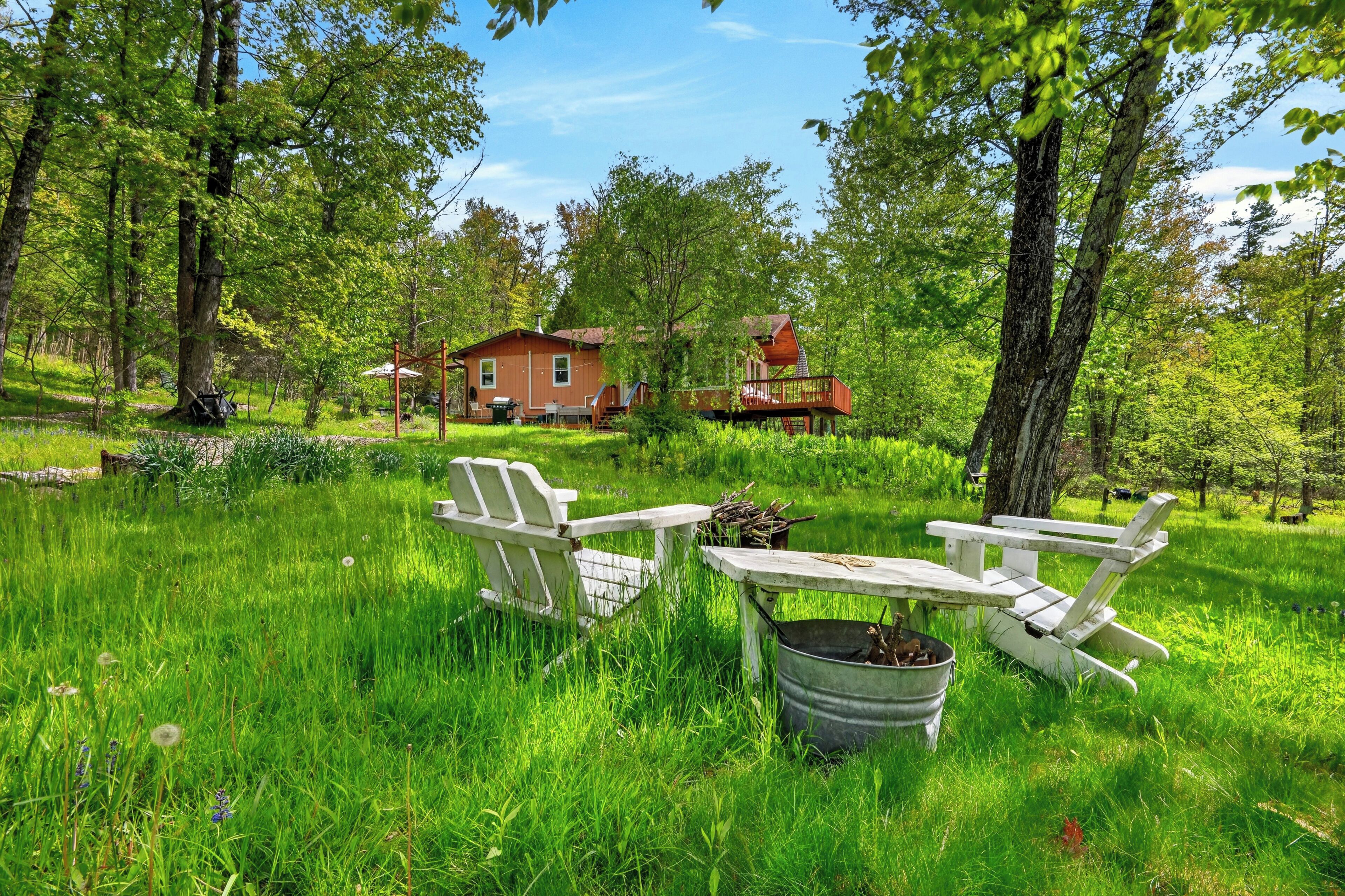 A cabin with a deck, surrounded by lush greenery and trees.