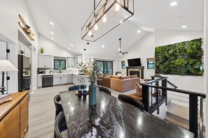 A modern kitchen with a dining area, a living room with a sofa, and a staircase. - Steps to Lake + Near Cave Rock + Heavenly Ski Resort | Tahoe Glen (Glenbrook)