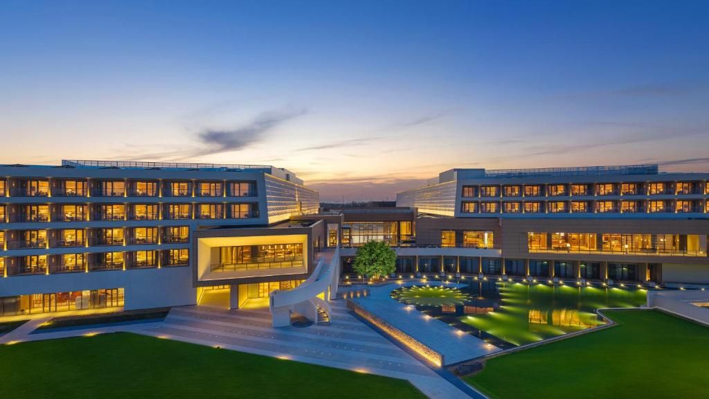 A modern hotel with multiple floors, a central courtyard, and a well-lit facade.
