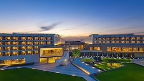 A modern hotel with multiple floors, a central courtyard, and a well-lit facade.