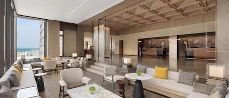 A spacious lobby with seating areas, a reception desk, and a view of the ocean.