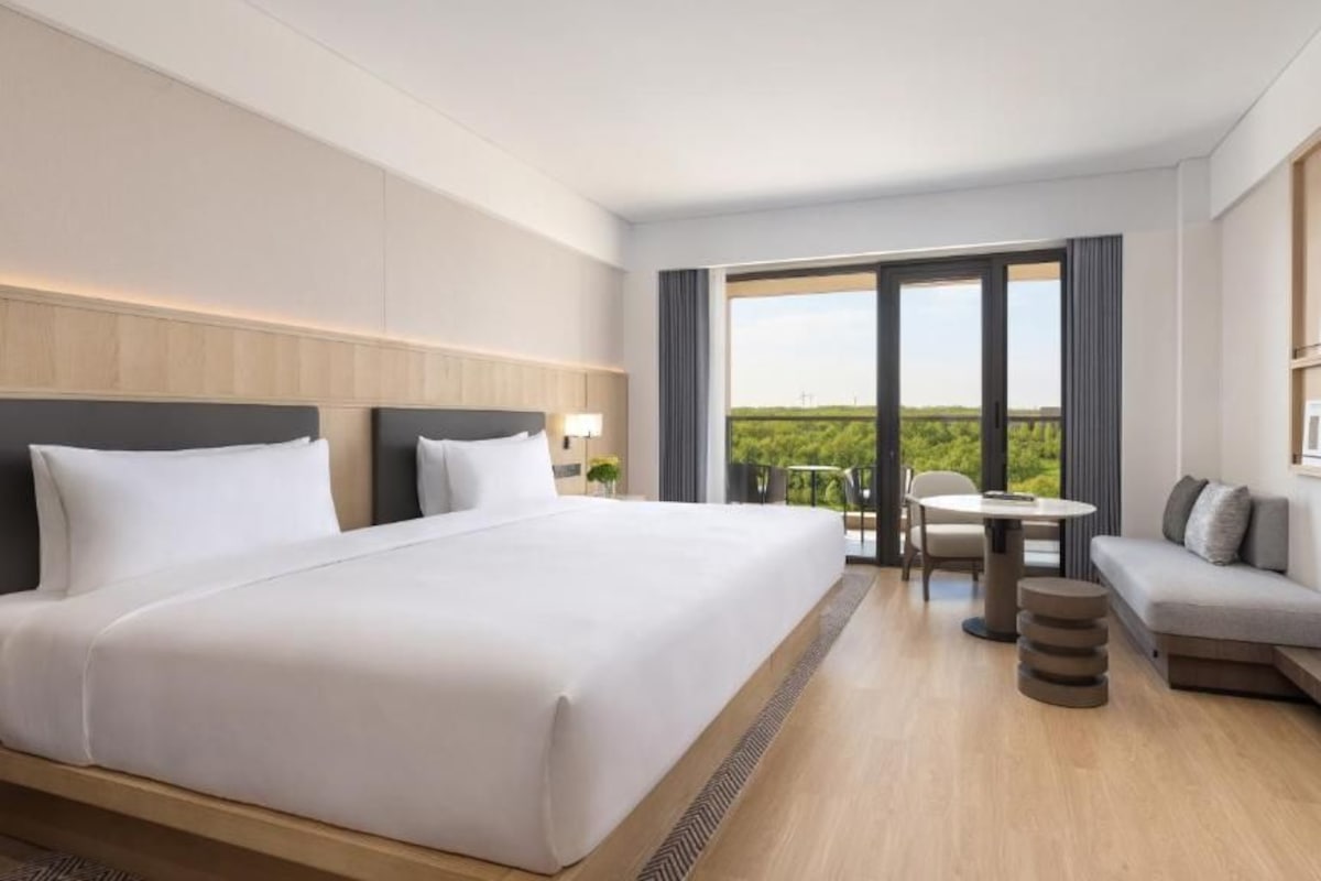 Quarto de hotel com uma cama grande, um sofá, uma mesa pequena e uma televisão.