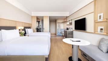 A hotel room with two beds, a TV, a small table, and a sofa.