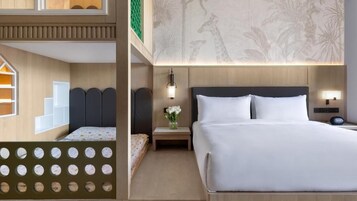 Habitación de hotel con cama, mesitas de noche, una pared con estampado de jirafa y ventana con vista a palmeras.