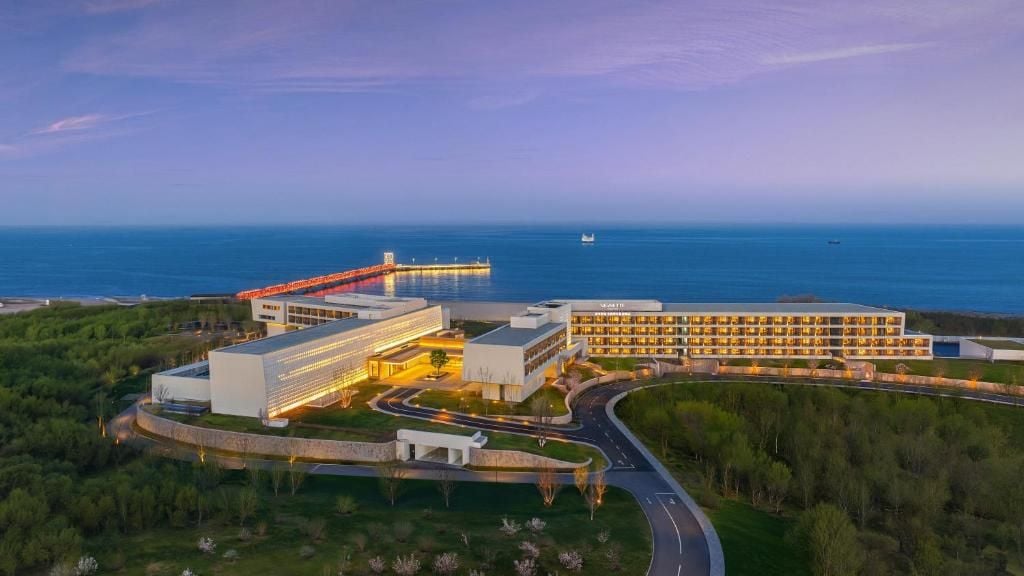 Um hotel com vários edifícios, área de estacionamento e vista para o mar.