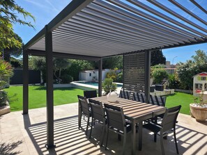 A covered patio with a table and chairs, a pool in the background, and a well-maintained lawn. - Villa with swimming pool, not overlooked, in quiet town center - sea 15 minutes away (Marignane)