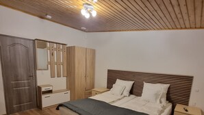 A bedroom with a bed, wooden wardrobe, bedside table, and a ceiling light fixture. - Karlskovhuset - Modern & Cozy, 8km from Legoland (Give)