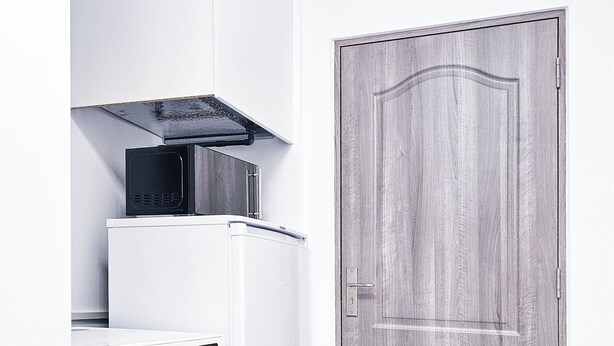 A compact laundry area with a washing machine and dryer, a wooden door, and a tiled floor. - Karlskovhuset - Modern & Cozy, 8km from Legoland (Give)