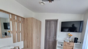 A room with a wooden wardrobe, a white dresser, a TV mounted on the wall, and a door. - Karlskovhuset - Modern & Cozy, 8km from Legoland (Give)