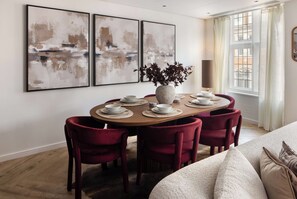 A dining area with a round table, six chairs, and three abstract paintings on the wall. - 3 Mins Walk to Westminster Abbey, Luxury Retreat (Greater London)