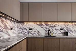 A modern kitchen with marble countertops, wooden cabinets, and under-cabinet lighting. - 3 Mins Walk to Westminster Abbey, Luxury Retreat (Greater London)