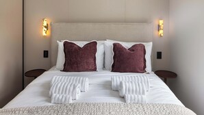 Un lit bien fait, avec des draps blancs, deux oreillers et une serviette blanche pliée.