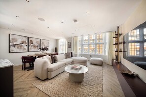 A modern living room with a sectional sofa, a round coffee table, and a dining area with a table and chairs. - 3 Mins Walk to Westminster Abbey, Luxury Retreat (Greater London)