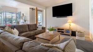 Sala de estar com sofá, mesa de centro, televisão e abajur.
