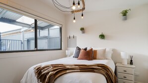 Quarto com cama grande, mesas de cabeceira, uma janela e vista para o exterior.