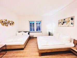 Ein Zimmer mit zwei Betten, einem Fenster und einer Heizung.