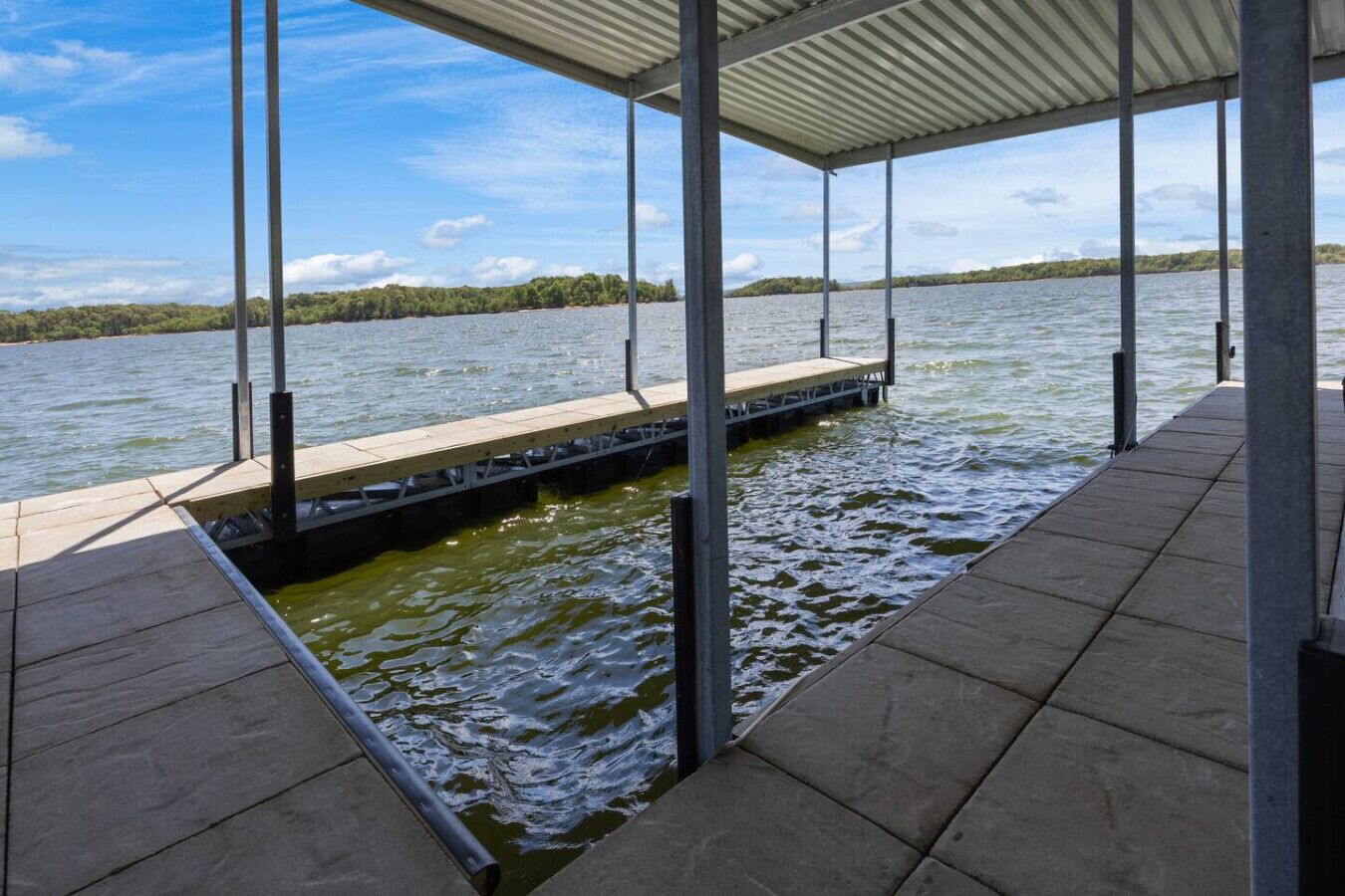 A covered dock extending into a body of water with a clear sky above.