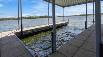 A covered dock extending into a body of water with a clear sky above.